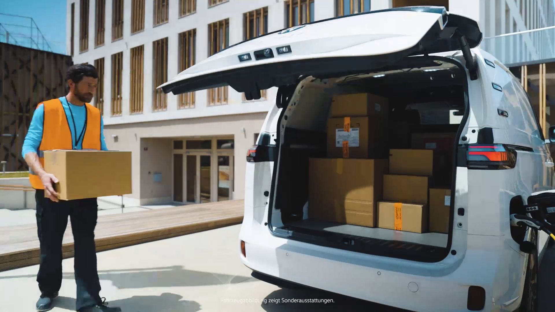 Ein ID. Buzz Cargo wird über das Heck von einem Paketboten mit Pakete beladen