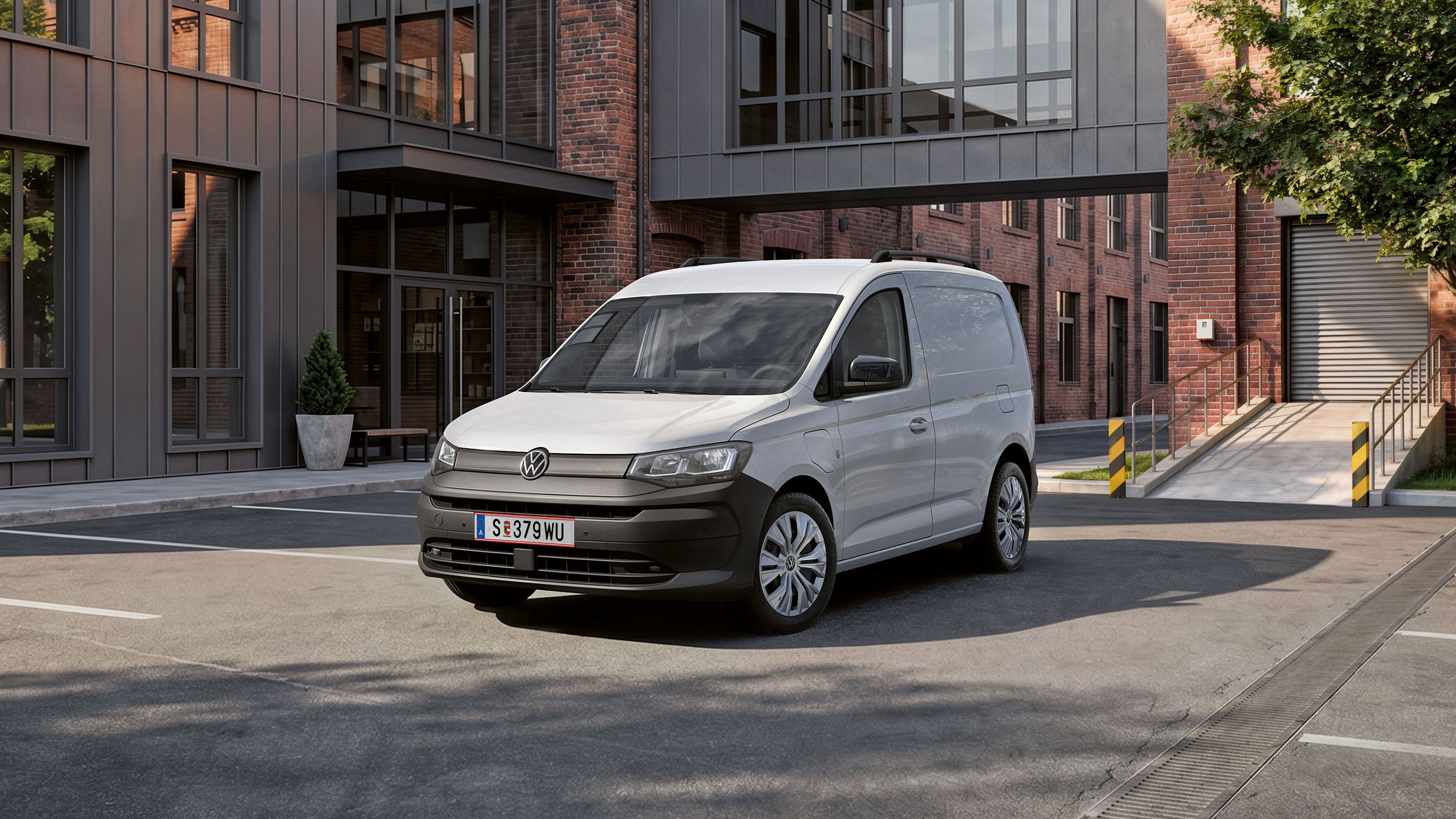 Biely Caddy Cargo stojí pred verejnou budovou.