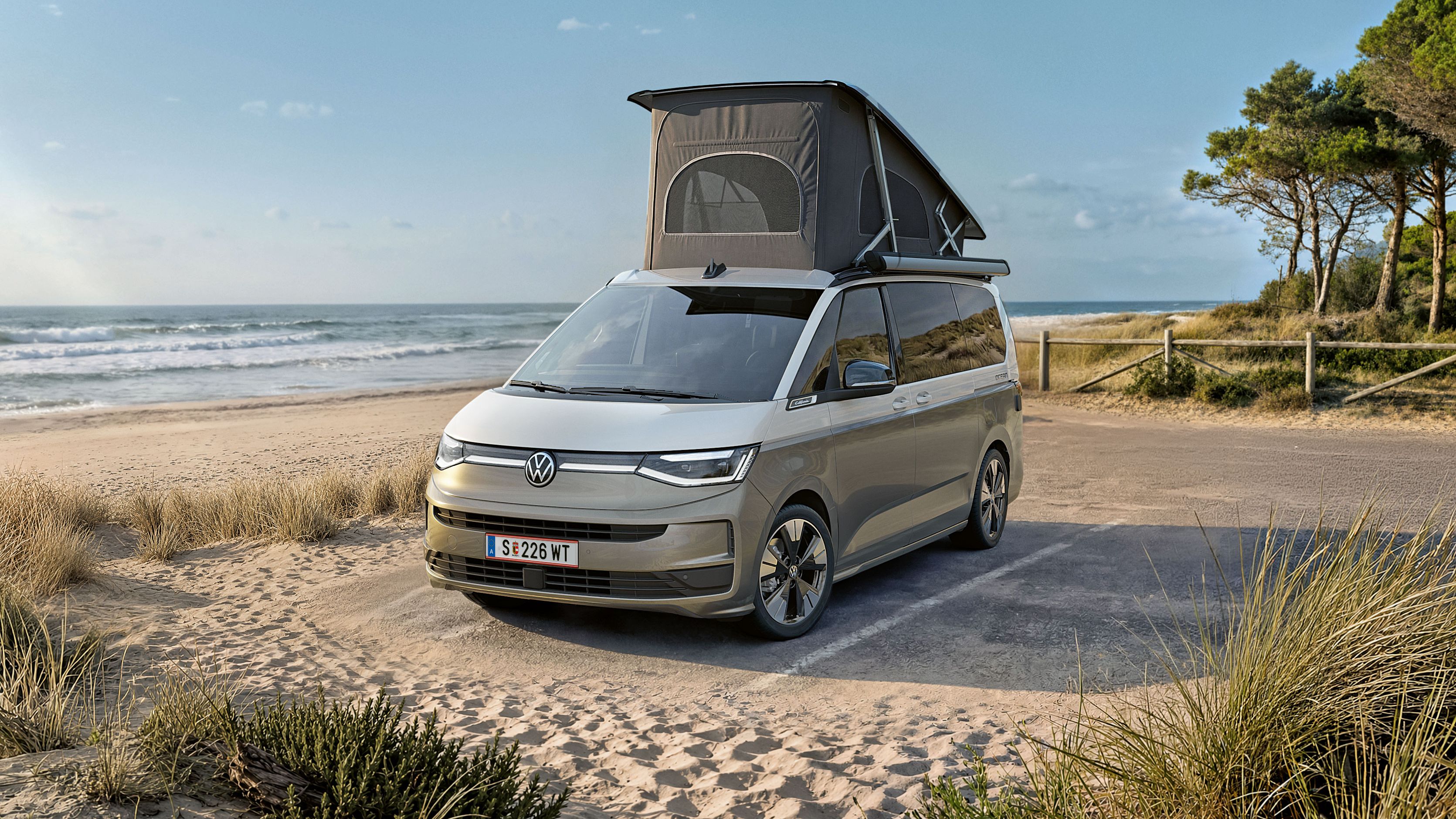 Nový VW California 2026 je zaparkovaný na pláži pri mori.