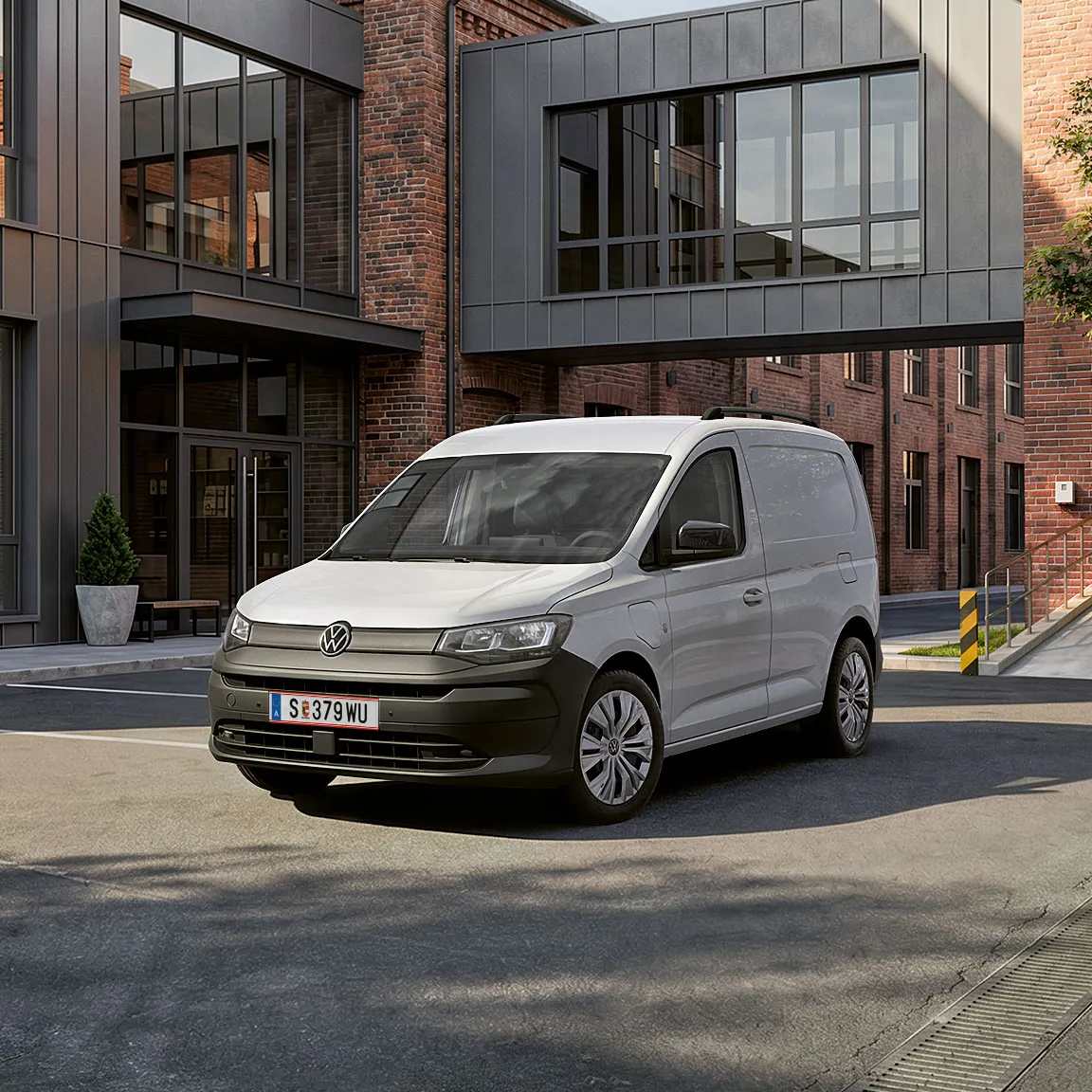 Biely Caddy Cargo stojí pre verejnou budovou.