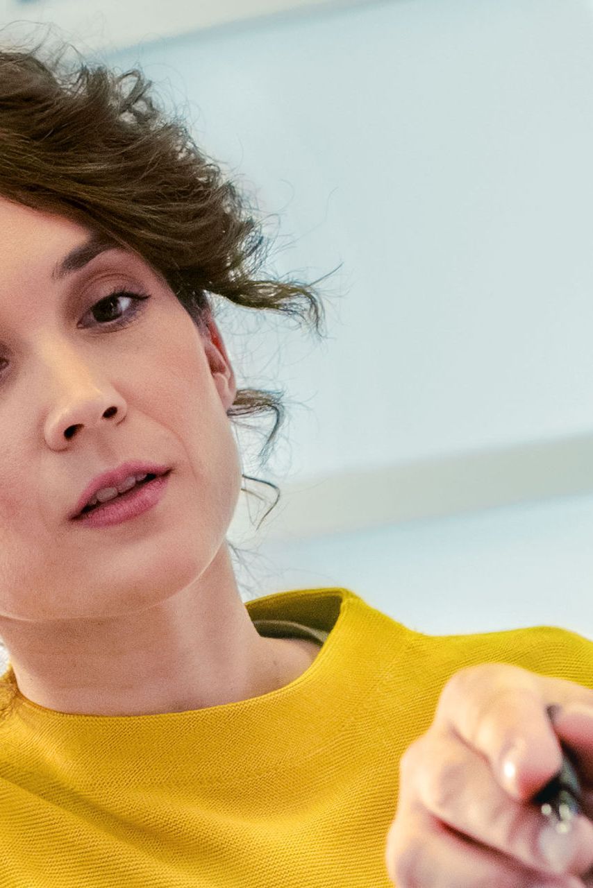 Dvaja ľudia diskutujú a ukazujú na niečo mimo záber. Jeden z nich drží pero. Obaja majú rozmazané tváre.